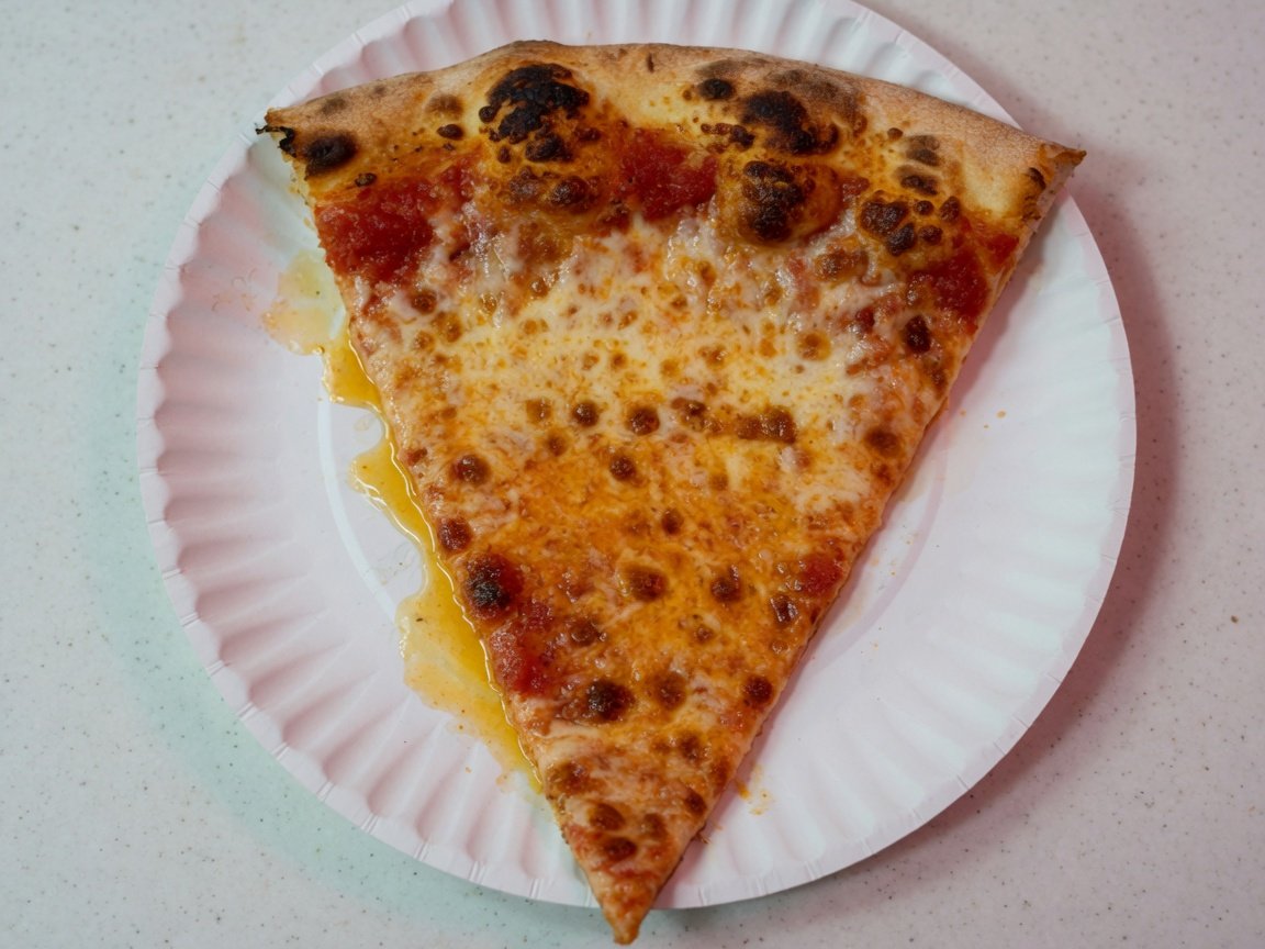A classic New York cheese slice on a paper plate